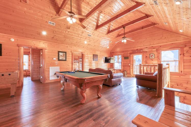 Inside a large cabin game room with a pool table, foosball table and couches